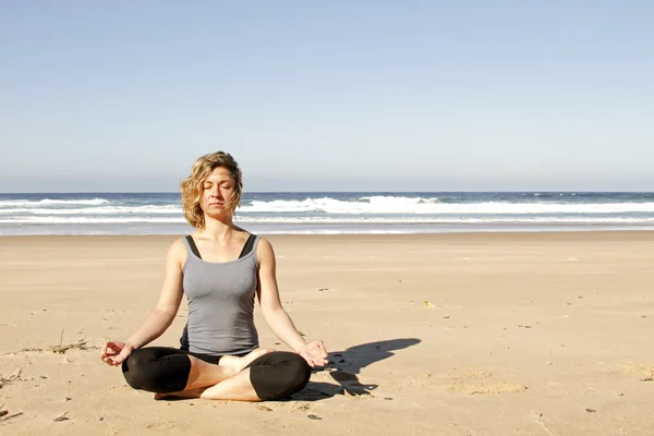 Junge gesunde Frau meditiert am Strand — Stockfoto