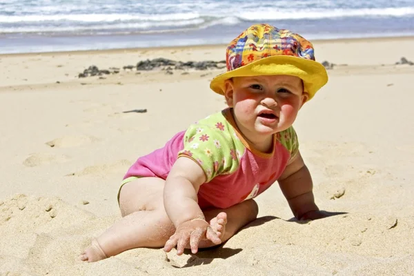 Sevimli küçük bebek kız plajda kuma oturmuş — Stok fotoğraf