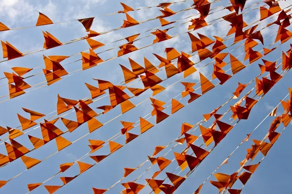 Malé oranžové vlajky proti modré obloze — Stock fotografie