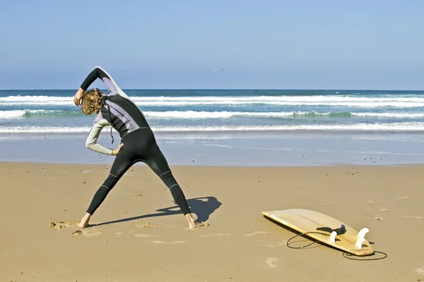 Young guy doing exercises before going to surf — Stock Photo, Image