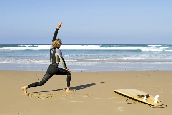 Young guy doing exercises before going to surf — Stock Photo, Image