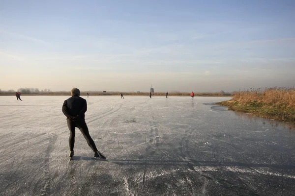 通常オランダ: 冷たい winterday の風車を望む凍った湖でスケート — ストック写真