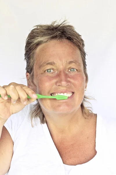Beautiful middle aged woman brushing her teeth — Stock Photo, Image