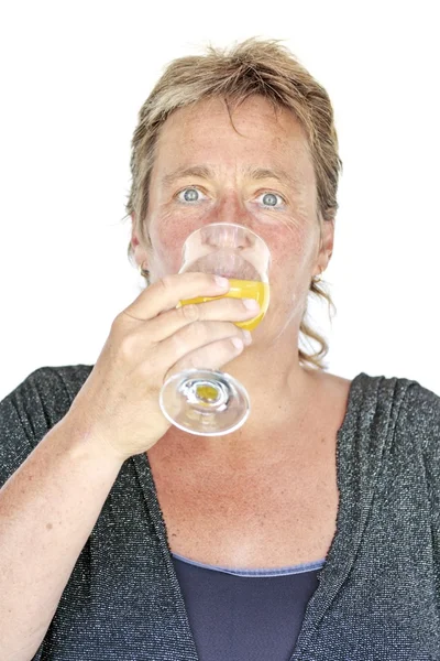 Średniej wieku kobieta wypija szklankę soku pomarańczowego — Zdjęcie stockowe