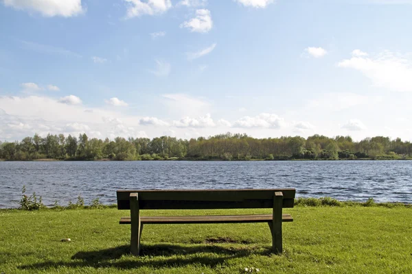 Bench at the water front from a lake — Zdjęcie stockowe