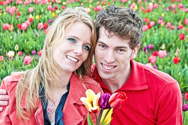 Unga lyckliga par i fälten tulip från Nederländerna — Stockfoto
