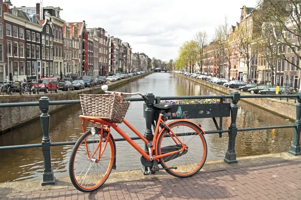 Pomarańczowy rower na moście w Amsterdamu w Holandii — Zdjęcie stockowe
