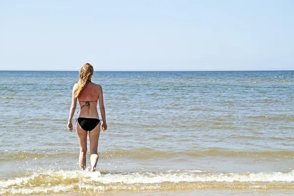 Young blonde woman walking into the ocean — Stock Photo, Image