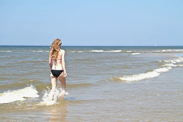 Mujer joven corriendo a través del agua del océano — Foto de Stock