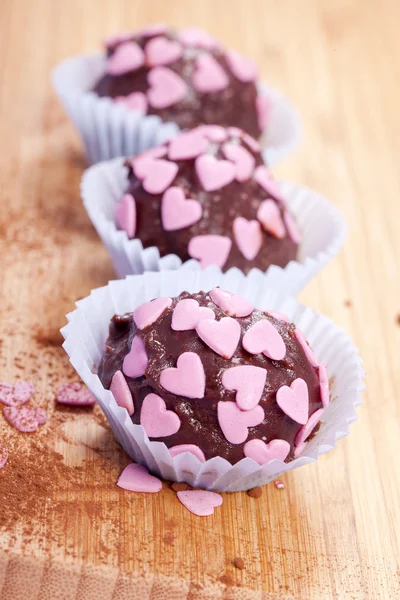 Chocolate pralines with pink hearts — Stock Photo, Image