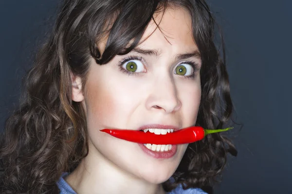Woman holding chili in her mouth — Stock Photo, Image