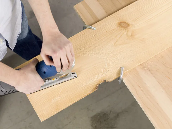 Overhead image of a man cutting sheet of a wooden plank — Stock Photo, Image