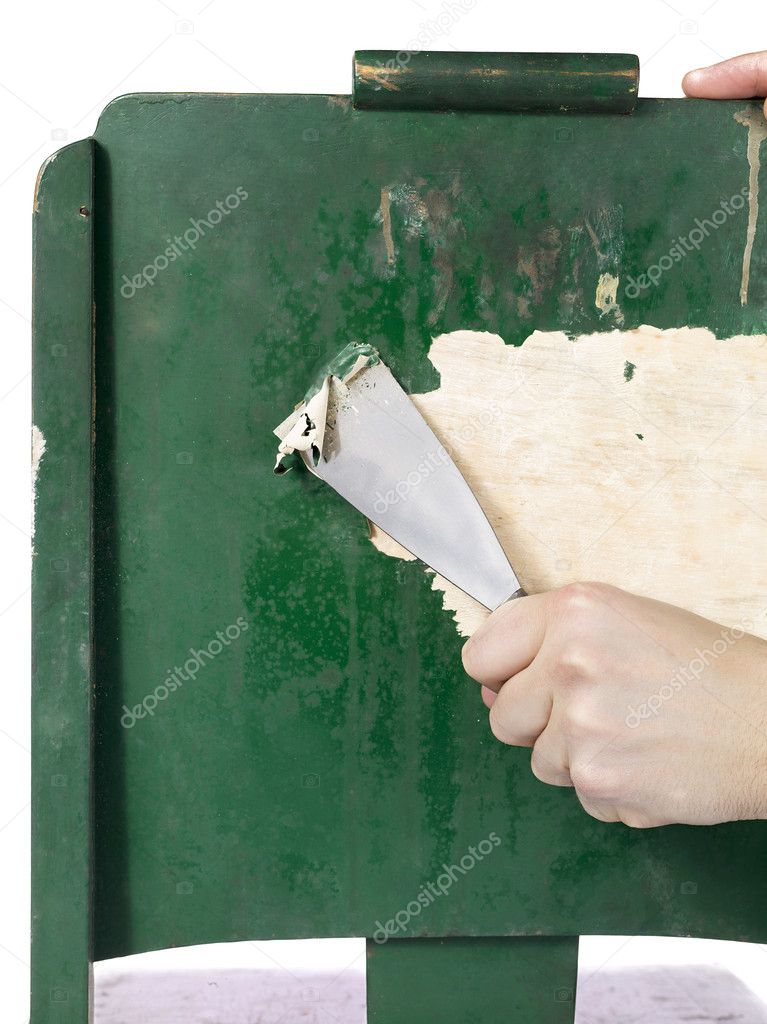 Hand using trowel to strip paint from wood