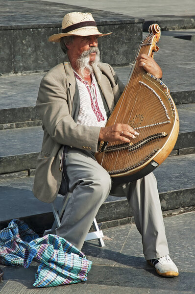 Colorful man in traditional dress playing the bandura