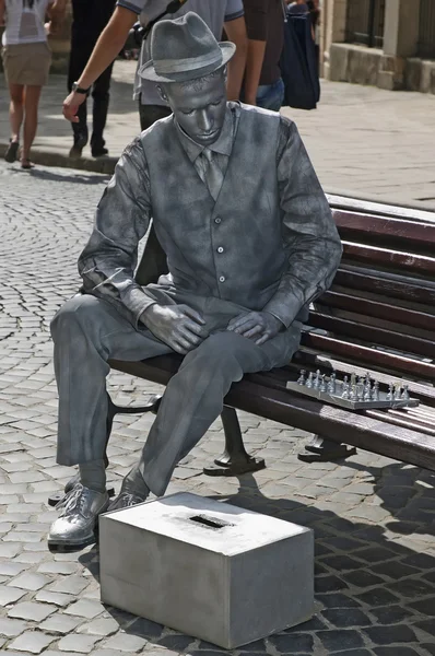 Живая статуя - человек, играющий в шахматы на скамейке — стоковое фото