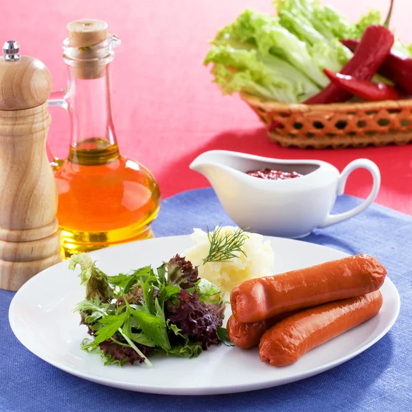 Sausages with potatoes and green salad — Stock Photo, Image