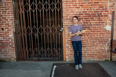 Man leaning on brick wall with pad of paper clipart