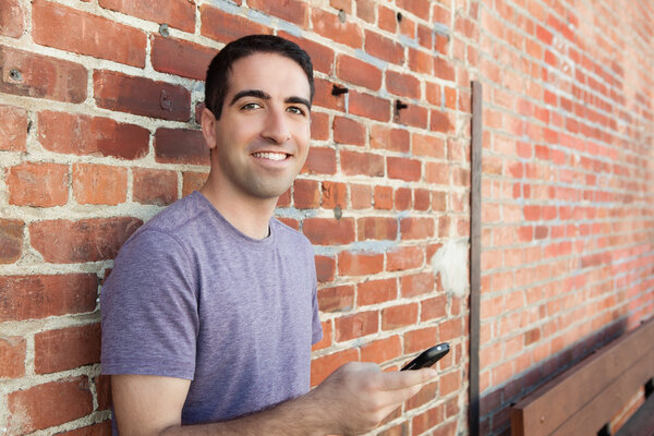 Парень опирается на стену с телефоном
