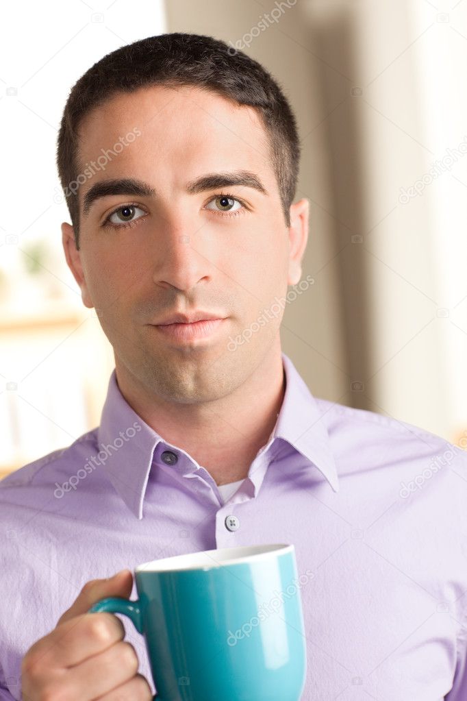 Cute guy with serious expression holding coffee mug