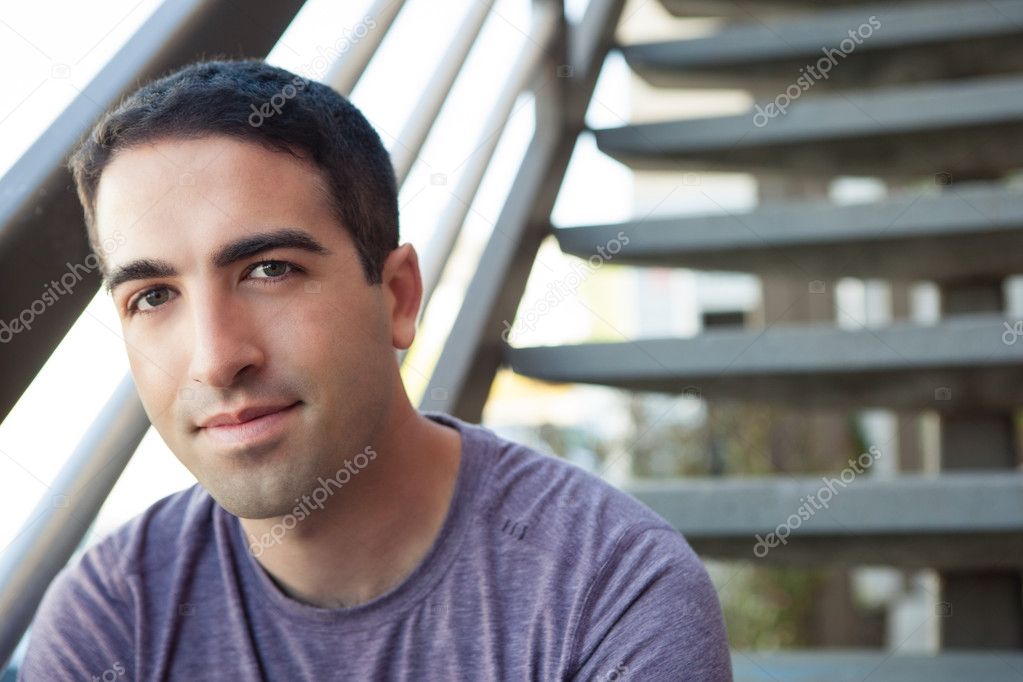 Cute young man sitting on stairs