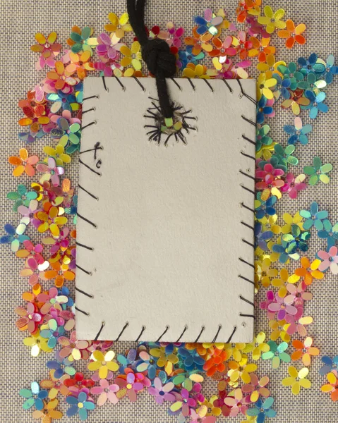Tag with handmade stitches over shiny floral decoration — Stock Photo, Image
