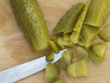 Pickled cucumbers cut on the wooden board clipart