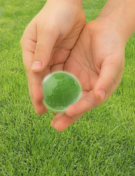 Groene planeet in de handen van het kind op het gras — Stockfoto