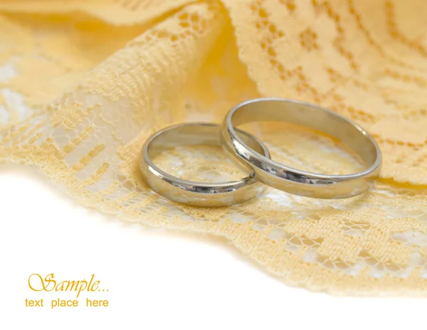 Anneaux de mariage dorés sur le fond textile jaune — Photo