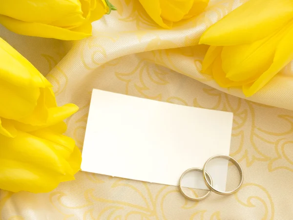 Nota de papel em branco com anéis de casamento e tulipas amarelas — Fotografia de Stock