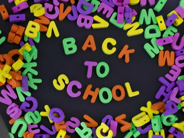 Powrót do szkoły tytuł napisany z gumy litery na czarnym tle — Zdjęcie stockowe