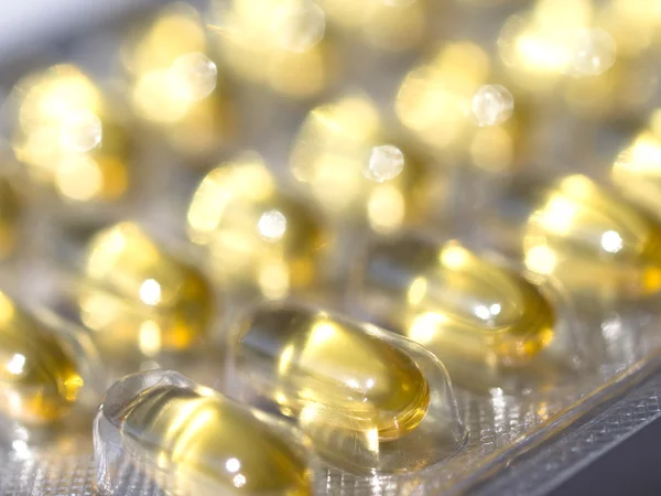 Желтые таблетки с маслом — стоковое фото