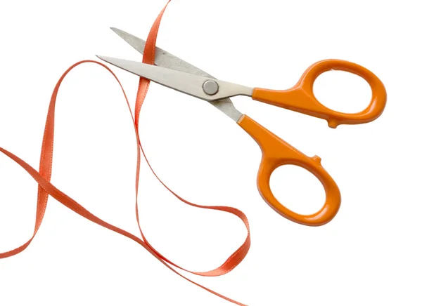 Orange scissors cutting orange ribbon — Stock Photo, Image