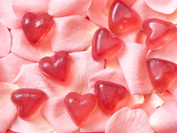 Corazones de goma sobre pétalos de rosa — Foto de Stock