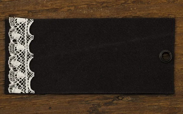 Étiquette noire avec dentelle sur le fond en bois — Photo
