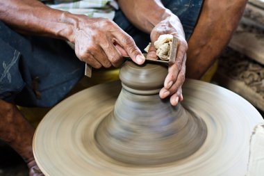 Potter's wheel and hands of craftsman hold a jug. clipart