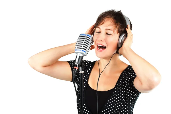 Νεαρή γυναίκα τραγουδώντας με ακουστικό και μικρόφωνο — Φωτογραφία Αρχείου