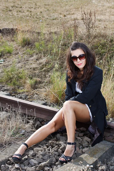 Blisko brunetka siedzi na kolei — Zdjęcie stockowe