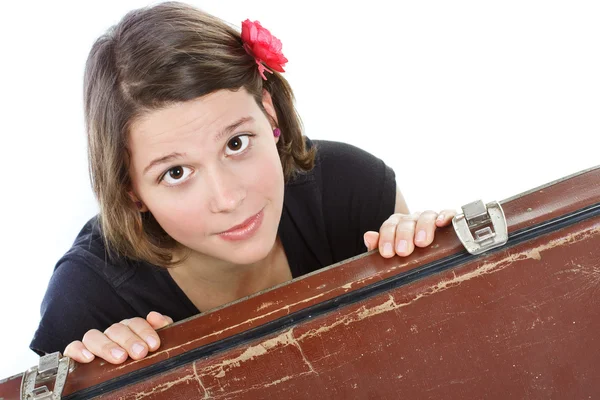 Atractiva joven mujer mirando desde detrás de una maleta — Foto de Stock