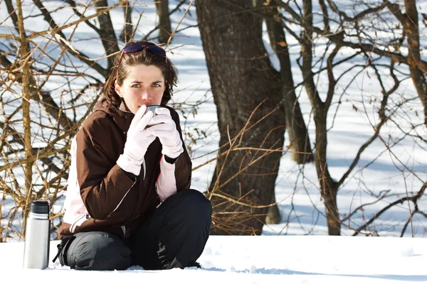 Junge Frau im Schnee mit Thermosflasche — Stockfoto