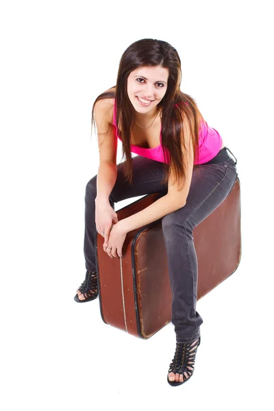 Beautiful young woman sitting on old suitcase — Stock Photo, Image