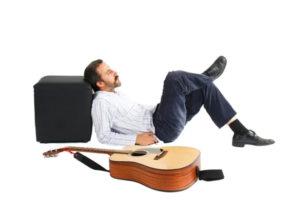 Человек лежит с гитарой впереди — стоковое фото
