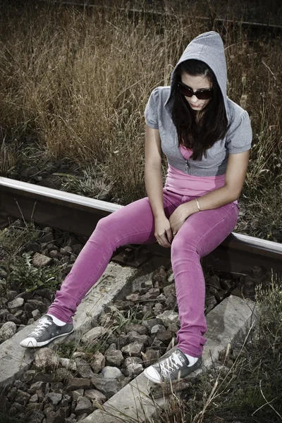Θλιβερή νεαρή γυναίκα που κάθεται επάνω σιδηρόδρομος — Φωτογραφία Αρχείου