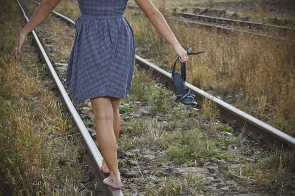 Jeune femme avec des chaussures à la main sur le chemin de fer — Photo