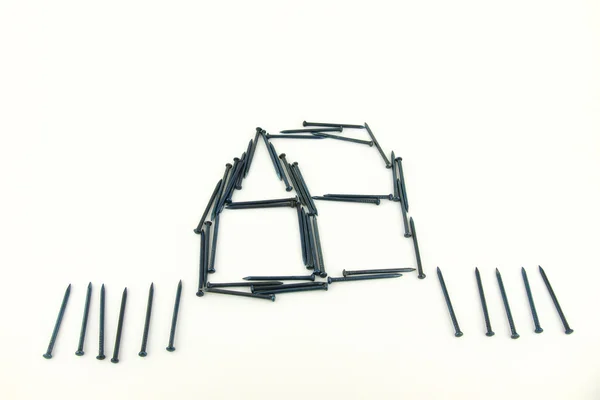 Steel nails construct house with fence — Stock Photo, Image