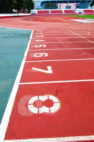Kırmızı bir yarış şeritleri numaraları ve stad içinde kırmızı koltuk ile izlemek — Stok fotoğraf