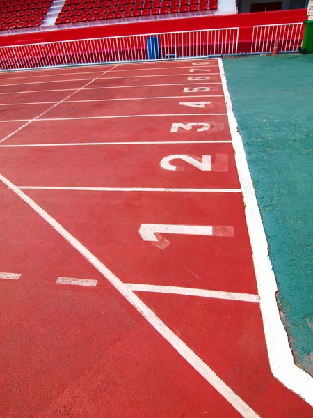 Kırmızı bir yarış şeritleri numaraları ve stad içinde kırmızı koltuk ile izlemek — Stok fotoğraf