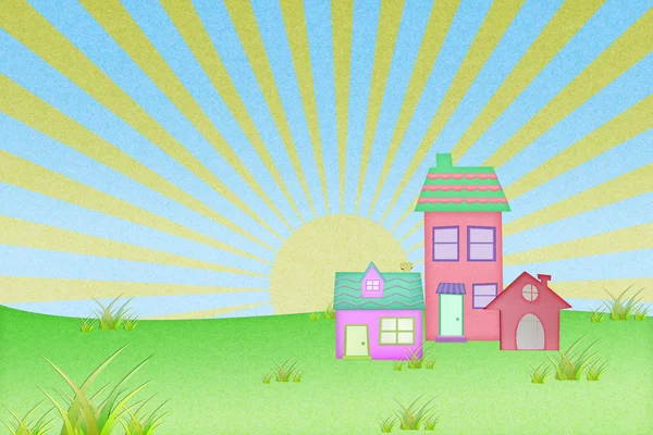 Casa da carta riciclata con campo di erba e sfondo tramonto — Foto Stock