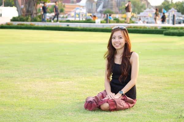 Portret atrakcyjny azjatycki kobieta siedzi na zielonej trawie fiel — Zdjęcie stockowe
