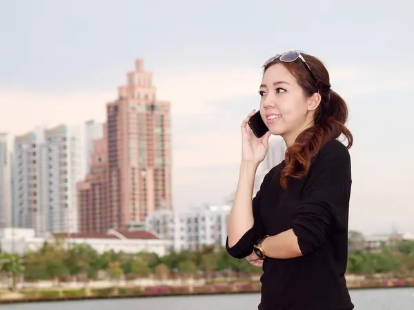 Jonge mooie Aziatische bellen via de telefoon met de bouw van de achtergrond — Stockfoto