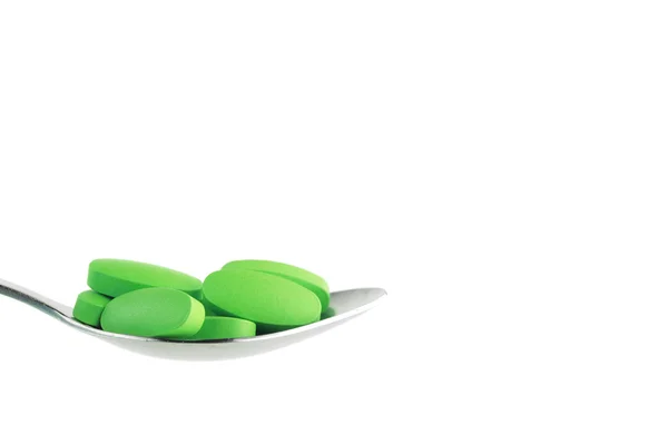 Green tablet on the spoon — Stock Photo, Image